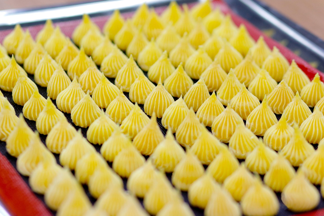 Vaso di crema al limone pronta per farcire dolci, con limoni freschi sullo sfondo.